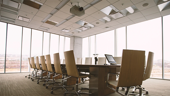 a conference room with long vertical windows and 20 chairs with wheels sitting around a table; photo used in blog post about unemployment tax costs for businesses