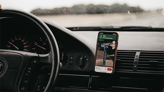 view of a car steering wheel and dashboard with a phone showing directions on a map; image used for blog about tax obligations for a side gig