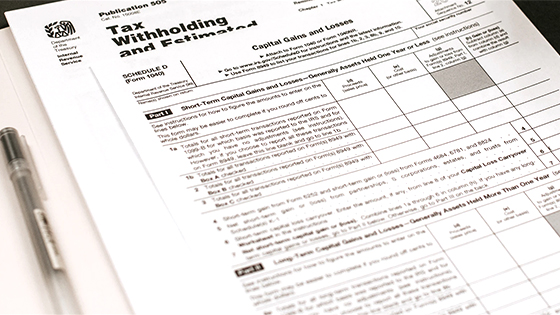 a black-ink pen lying next to tax withholding forms for a tax return