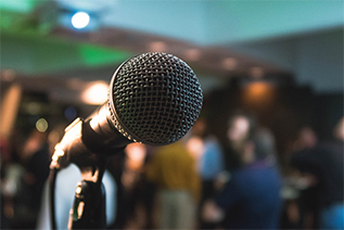 microphone in focus inside a conference room with people; image used for blog post about upcoming Houston events