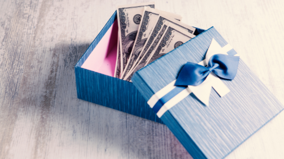 a box of one hundred dollar bills open on a wooden table; image used for blog post about 2021 gift tax return