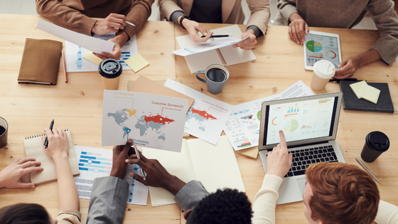 An image of six people at a table looking at financial documents; for blog post about accounting and development collaboration