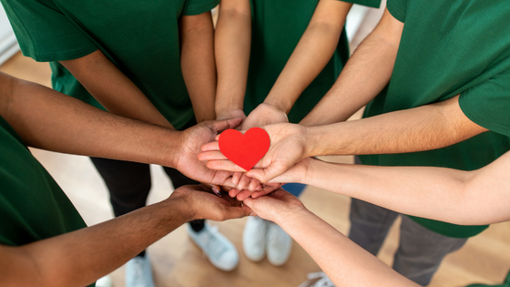 022423 – Does Your NFP Pass the Public Support Test – 560×315 A photo of a team of people putting their hands together in a huddle with a paper heart in the middle; for blog post about not-for-profits passing public support test