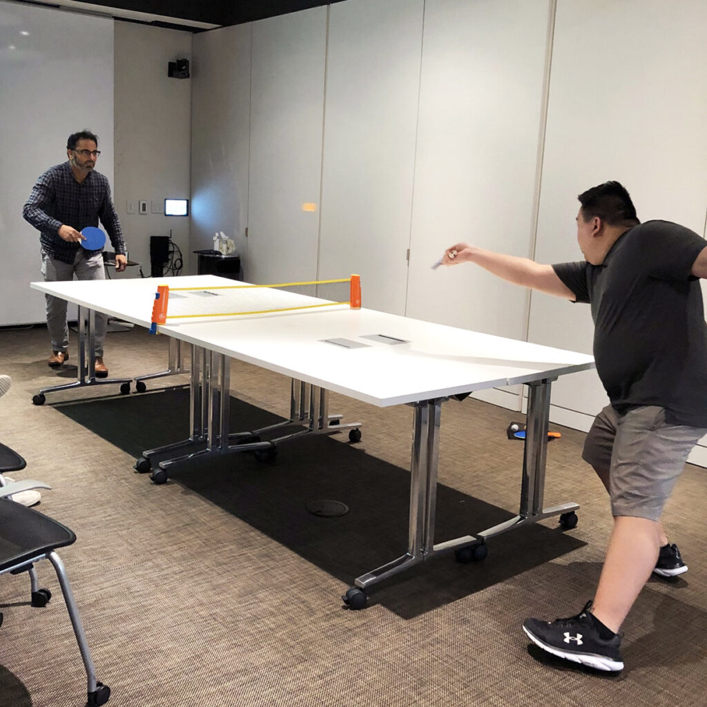 Photo of two PKF Texas team members playing ping pong at an office happy hour event